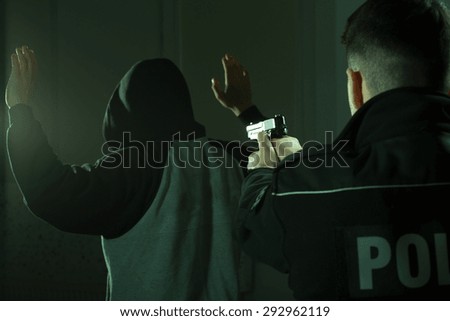 Image of a police officer keeping gun on a crook