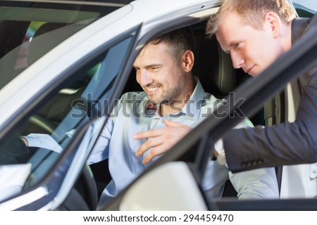 Client sitting in new car and talking with salesman