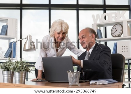 Elderly man showing something aged woman on his laptop