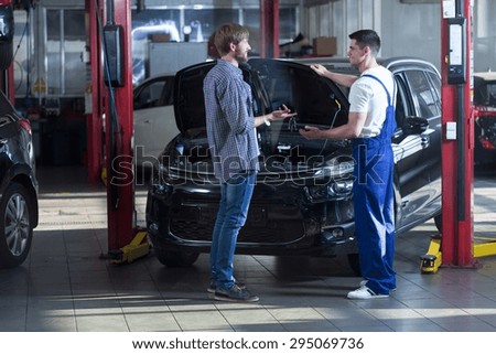 Young automotive technician talking with male client