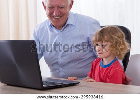 Happy man learning little grandson to use new technology
