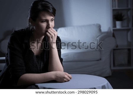 Young lonely sad widow sitting in empty dark room
