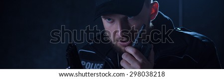 Police officer is holding a shortwave radio and gun