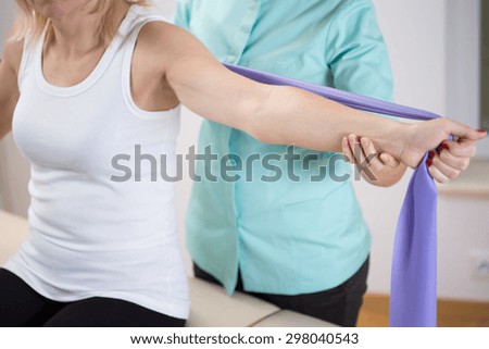 Woman at physiotherapist office exercising with band