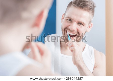 Pretty young man brushing his perfect teeth