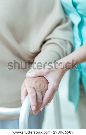 Close up of medic holding aged patients hand