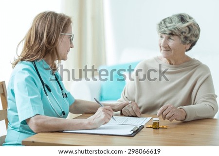 Female doctor on medical home appointment talking with elderly patient