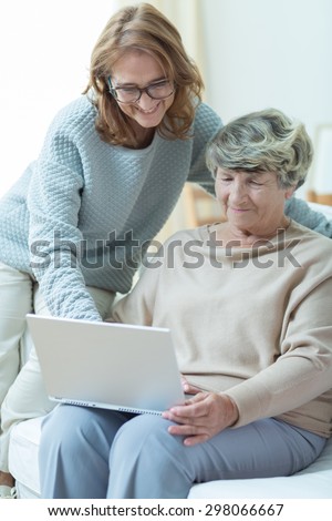 Picture of smiling carer teaching old woman computer skills