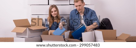 Young married couple during packing and full of boxes