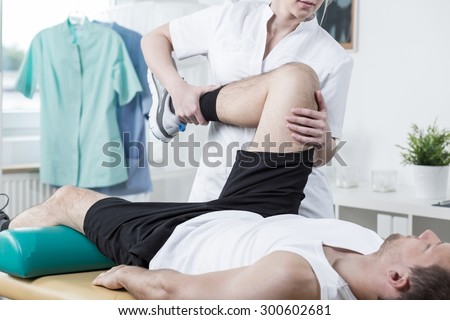 Female physiotherapist training leg of young man