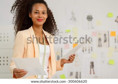 Picture of young happy businesswoman in fashion design atelier
