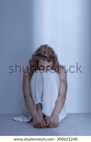 Curled up scared rape victim in empty room