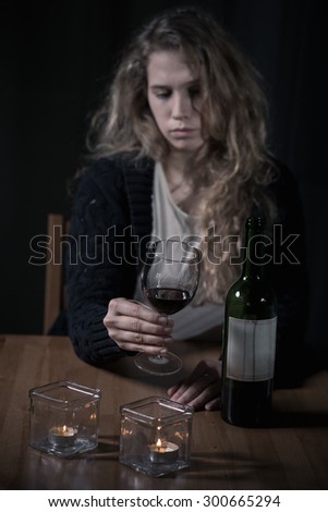 Pretty sad woman drinking wine during lonely evening at home