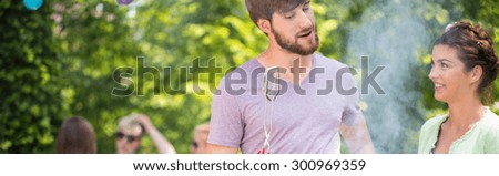 Panorama of man talking with his friend during garden party