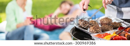 Panorama of man grilling meat and vegetables for outdoor dinner