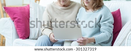 Carer is showing elder lady how to use computer