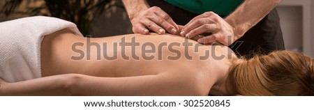 Young woman having acupressure treatment for back pain