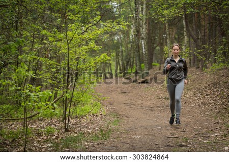 Happy active woman running on forest path