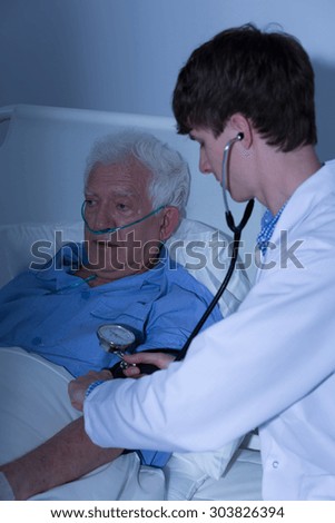 Doctor controlling blood pressure of elder man