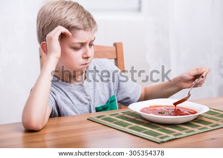 Unhappy picky child eating creamy tomato soup