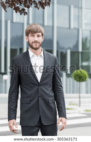 Young attractive man in suit in front of his company