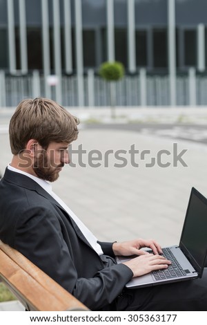 Man sitting outside company using laptop to work