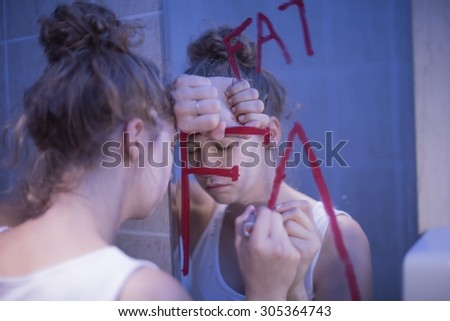 Picture of bulimic girl and red writing fat on mirror