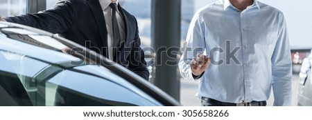 Panoramic view of two elegant men standing by the car