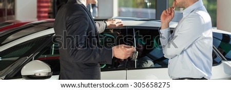 Elegant man buying new expensive car from car dealer