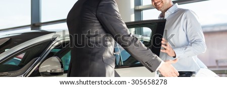 Panoramic view of young elegant man getting into the car