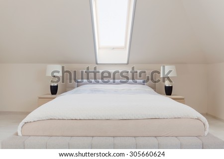 Big white double bed in simple white bedroom