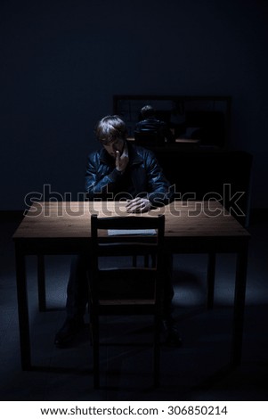 Arrested man sitting in dark empty room