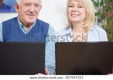 Two elderly happy businesspeople sitting with computers