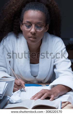 Forgetful female student doing homework at night