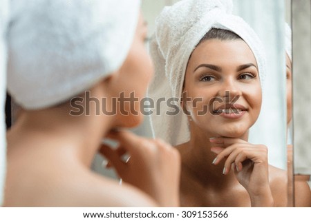 Beautiful and smiling woman looking at the mirror