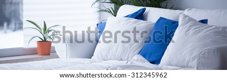 Panorama of comfortable bed with neat white and blue bedding