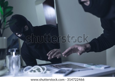 Thief in balaclava breaking into the house