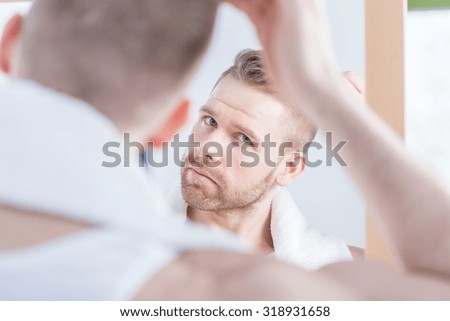 Image of handsome man watching himself in the mirror