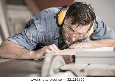 Focused carpenter at work with wooden plank
