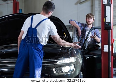 Image of young driver and auto service worker diagnosing car