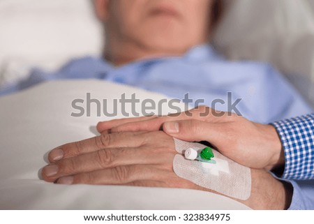 Close-up of an elder patient\'s hand covered with realative\'s hand