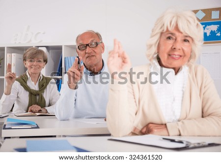 Photo of retired people raising their hands during lesson