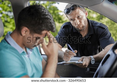 Man in a car and the policeman with traffic ticket