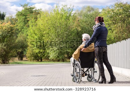 Disabled senior man and assistant in the park