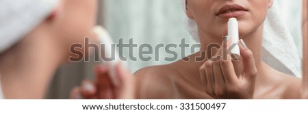 Panorama of young girl putting lip balm on her lips