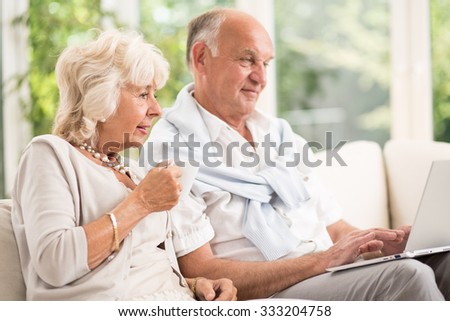 Image of modern elderly married couple using laptop