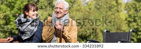 Disabled man with walking stick and wheelchair in park