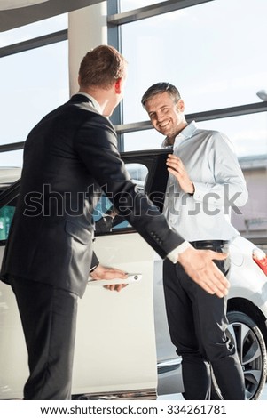 Photo of auto dealer and customer in elegant showroom