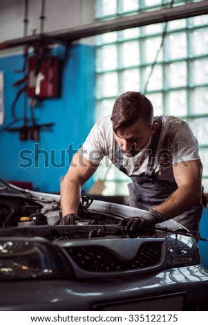 Male technician at car service station is repairing vehicle
