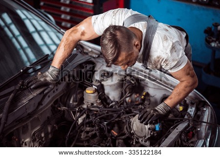 Male mechanic is checking parts of car bonnet